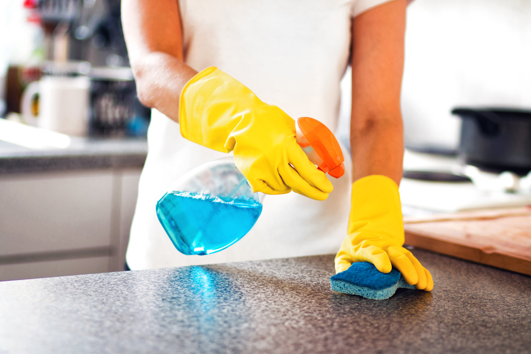 Woman Using Spray Polish To Clean Kitchen Surface. Woman cleaning kitchen